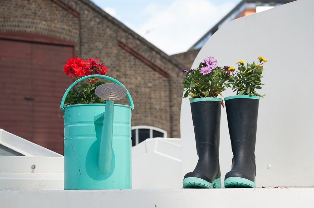 recycling old watering cans, wheelbarrows, tires and even rain boots   is a great way to brighten up your yard