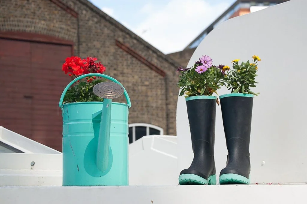 recycling old watering cans, wheelbarrows, tires and even rain boots is a great way to brighten up your yard
