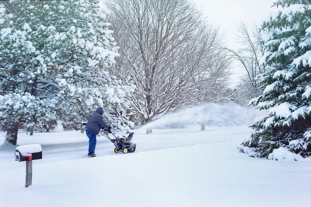 a man blows snow along his driveway