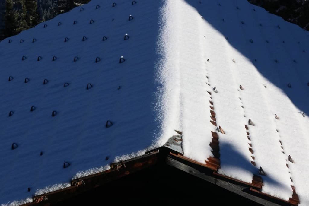 corrugated metal roof with snow guards and light snow on it