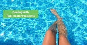 a person is seen from the legs down, with the legs hanging in crystal-clear pool water. text reads, dealing with pool heater problems
